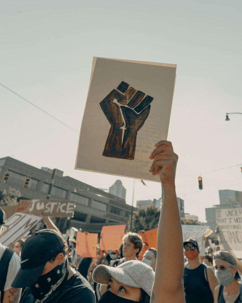Protesters holding up a poster of a black fist